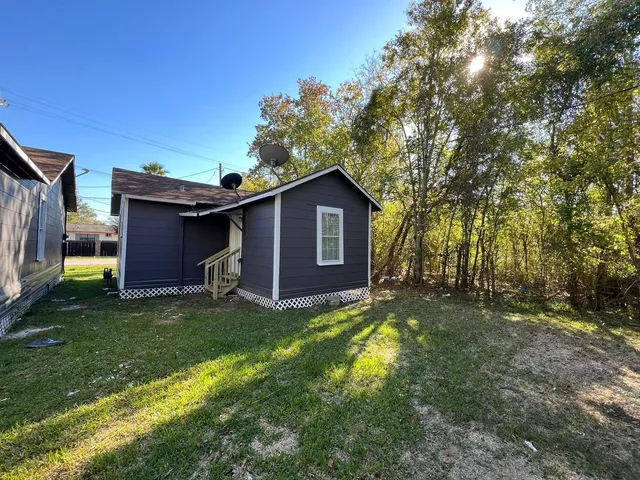a view of a yard in front of a house with large trees