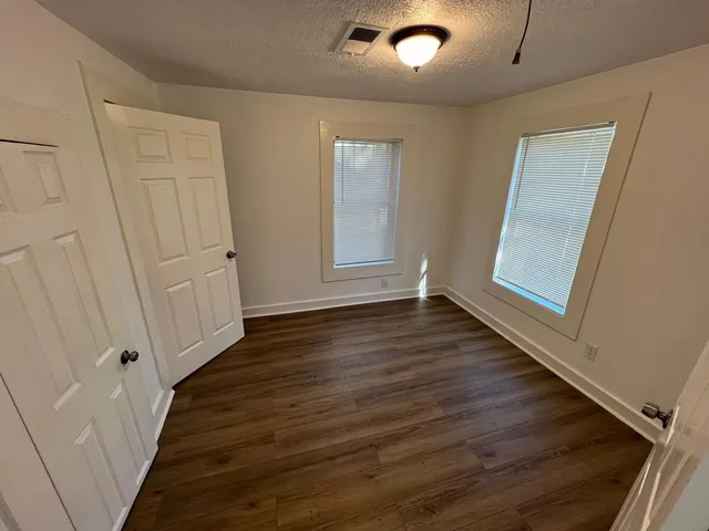 an empty room with wooden floor and windows