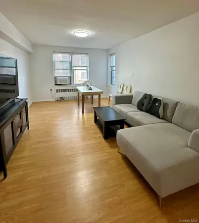 a living room with couches and kitchen view with wooden floor
