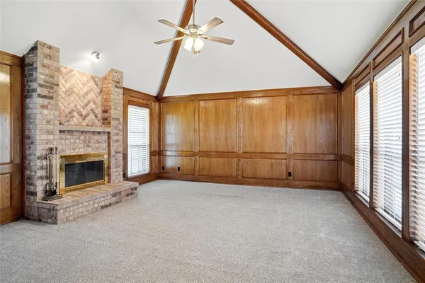 an empty room with windows fireplace and fan