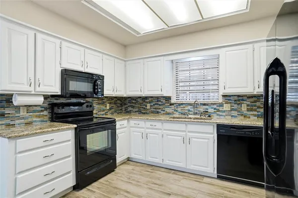 a kitchen with granite countertop white cabinets sink and stainless steel appliances
