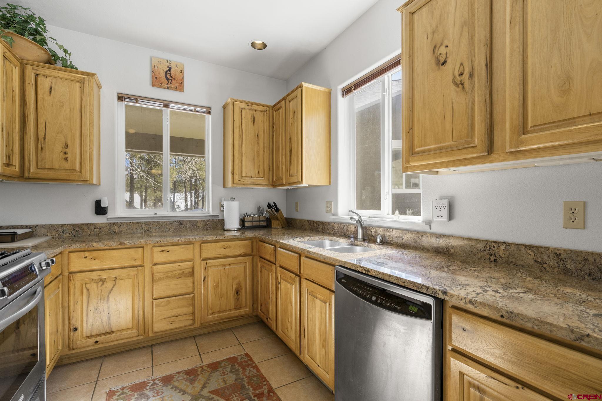 498 Woodbridge Way Durango, CO 81301 - Photo 8 of 26 a kitchen with granite countertop a sink stainless steel appliances white cabinets and a window