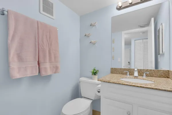 a bathroom with a granite countertop sink a toilet and mirror