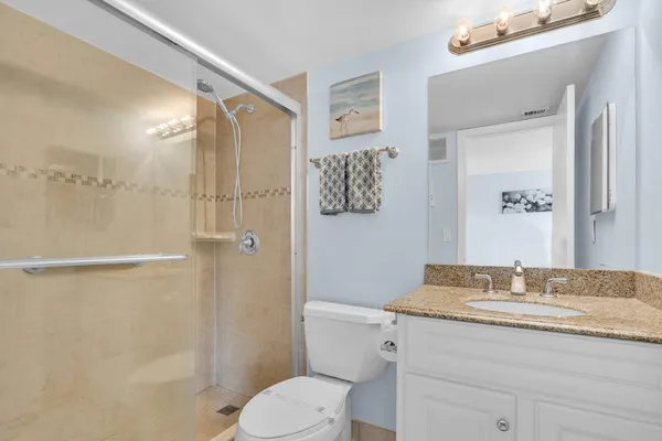 a bathroom with a granite countertop sink toilet and shower