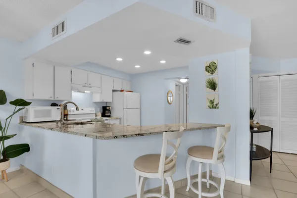 a kitchen with kitchen island granite countertop a sink and white cabinets