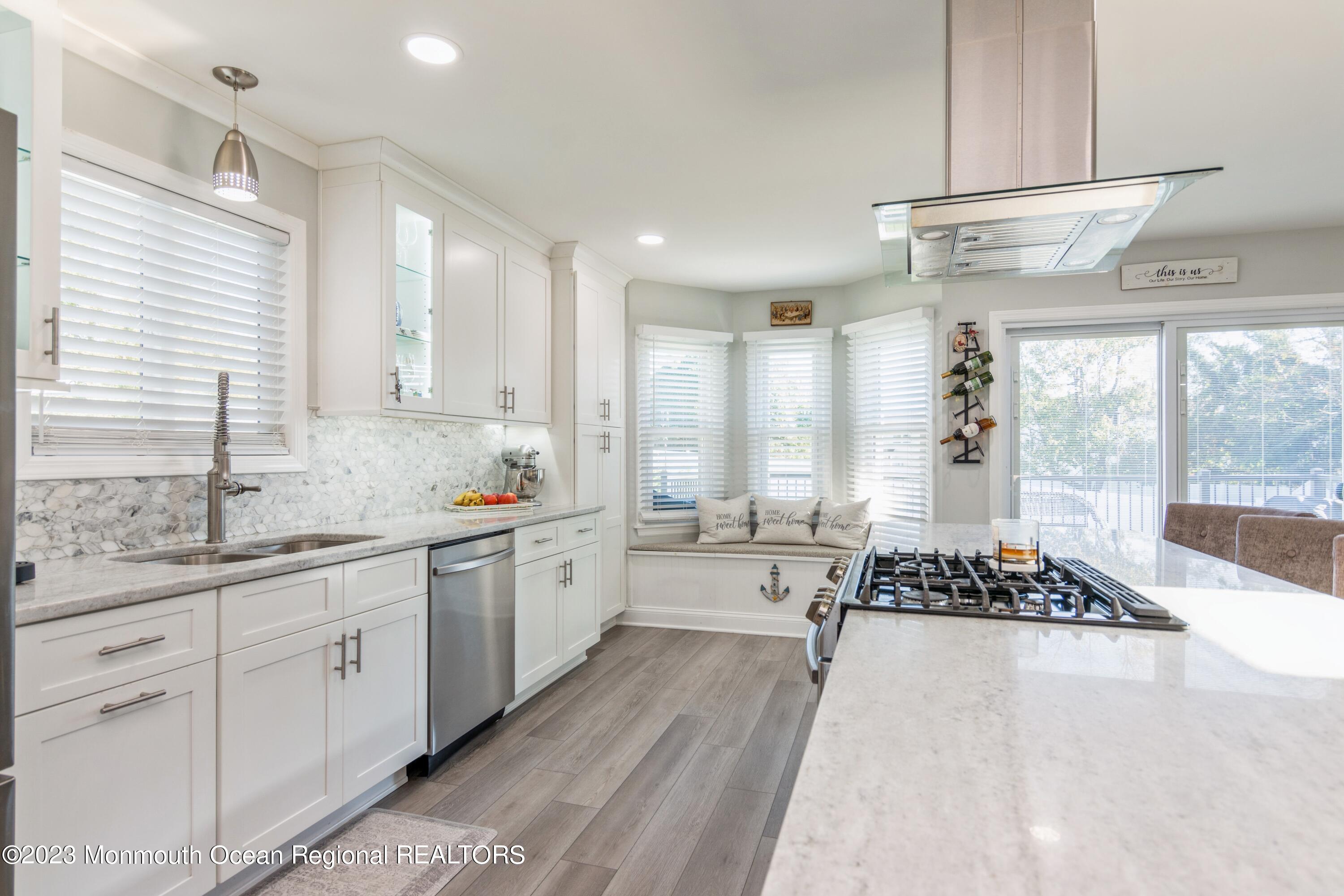 a large kitchen with kitchen island a large window a sink stainless steel appliances and cabinets