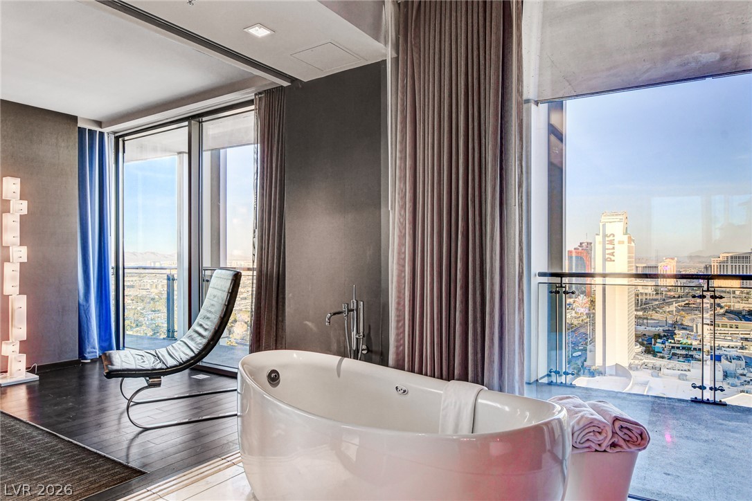 4381 West Flamingo Road, Unit 3002 Las Vegas, NV 89103 - Photo 57 of 59 Floor-to-ceiling windows frame cityscape views from this modern bathroom featuring a freestanding soaking tub.