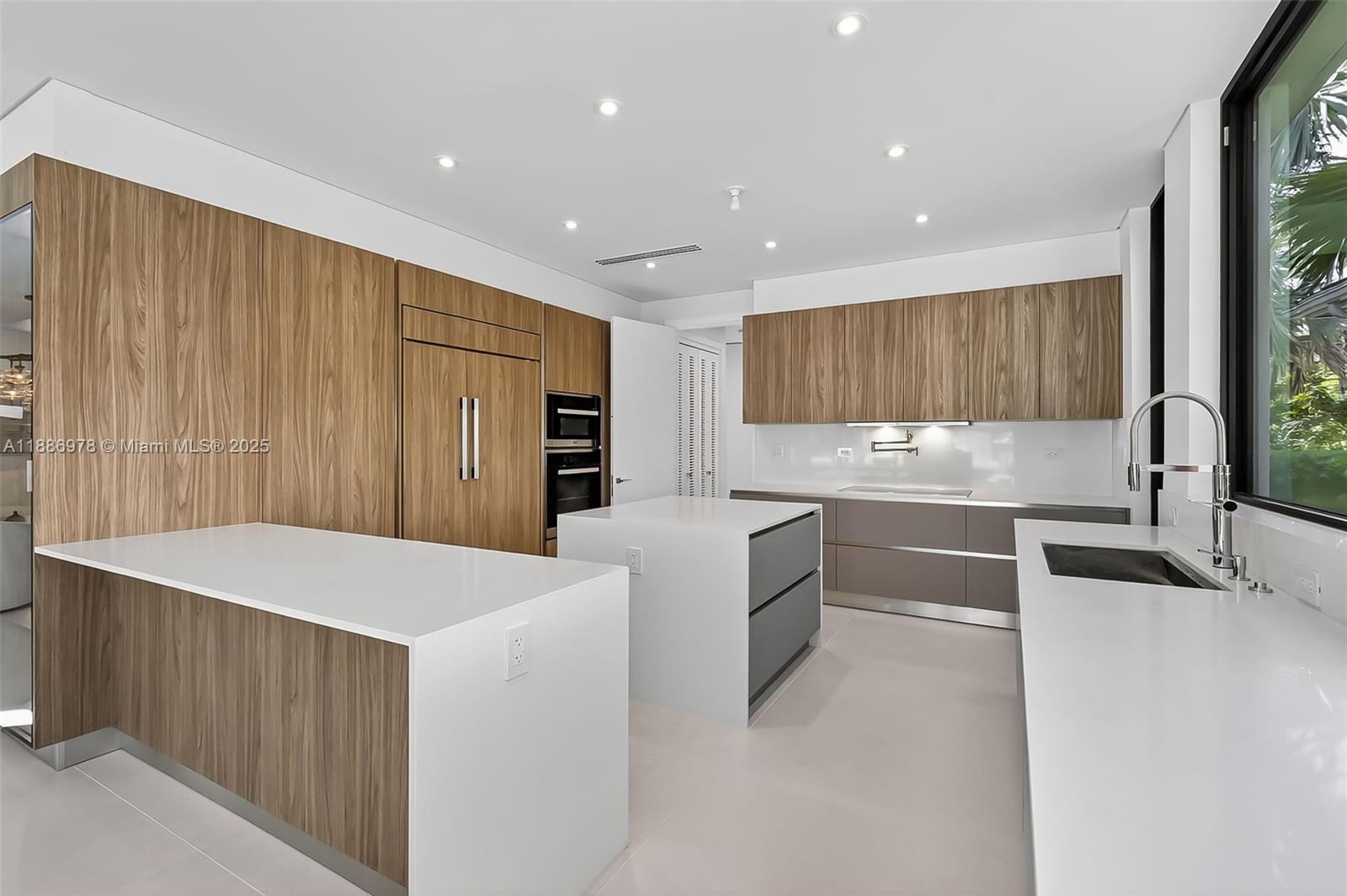 620 Solar Isle Drive Fort Lauderdale, FL 33301 - Photo 32 of 83 a large kitchen with stainless steel appliances a large counter top a stove a sink and a refrigerator with wooden floor