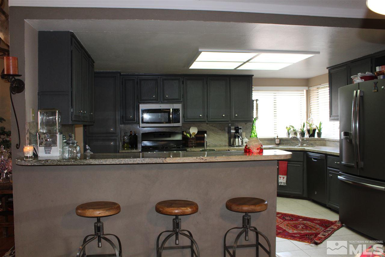 526 Citadel Road Reno, NV 89503 - Photo 8 of 22 a kitchen with stainless steel appliances granite countertop a sink a stove a refrigerator with a dining table and chairs