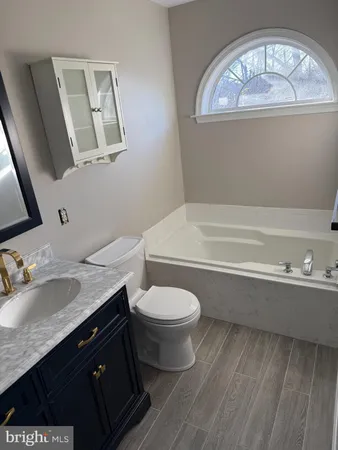 a bathroom with a granite countertop sink a toilet and bathtub