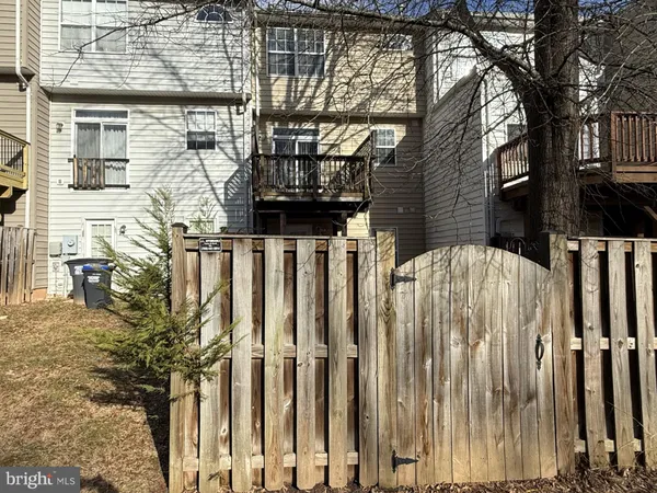 a view of a house with a wooden fence and a large tree