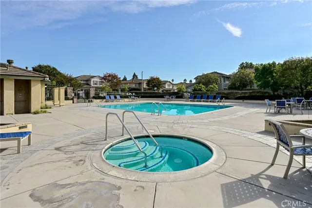 a small pool with lawn chairs and potted plants