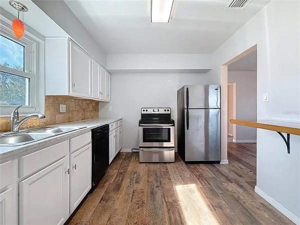 a kitchen with a refrigerator a sink and dishwasher with wooden floor