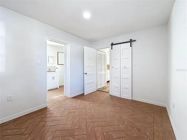 a view of a hallway with bathroom and wooden floor