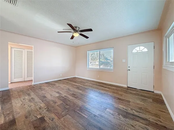 a view of empty room with wooden floor and fan