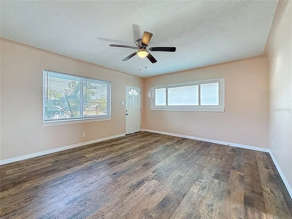 a view of empty room with wooden floor and fan