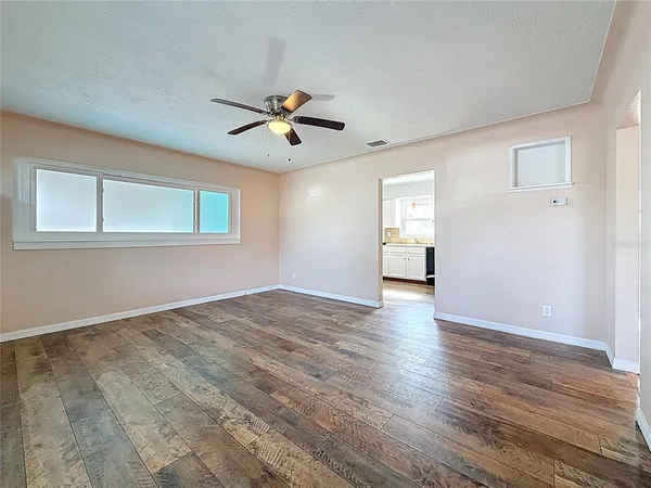 a view of empty room with wooden floor and fan