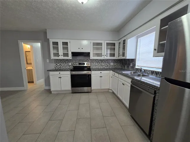 a kitchen with stainless steel appliances granite countertop a stove top oven a sink dishwasher and a refrigerator