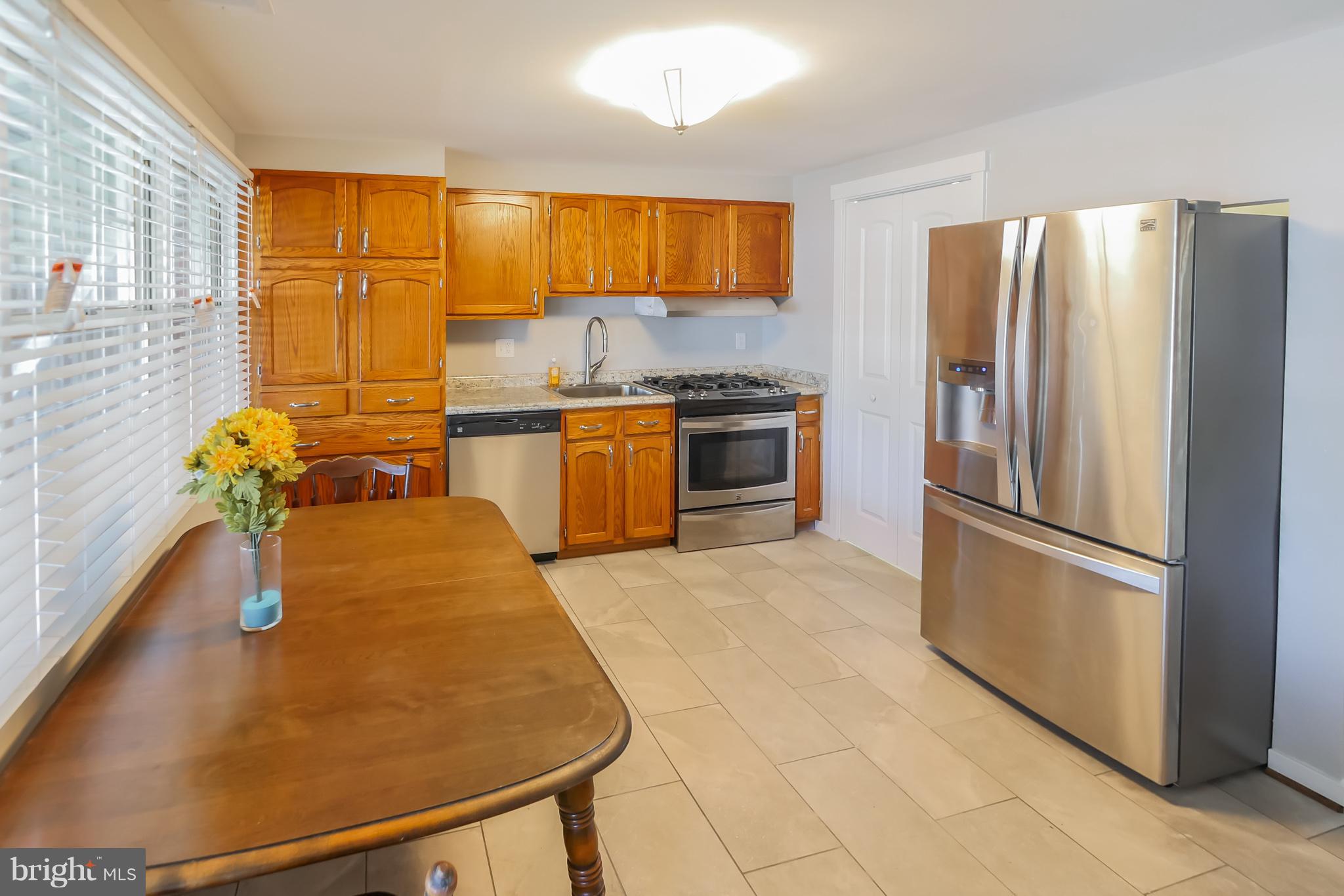 4410 Annapolis Road Baltimore, MD 21227 - Photo 8 of 31 a kitchen with stainless steel appliances granite countertop a refrigerator a sink a stove with wooden cabinets