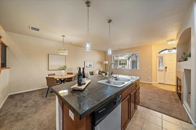 a kitchen with a stove a sink a counter top space and living room view