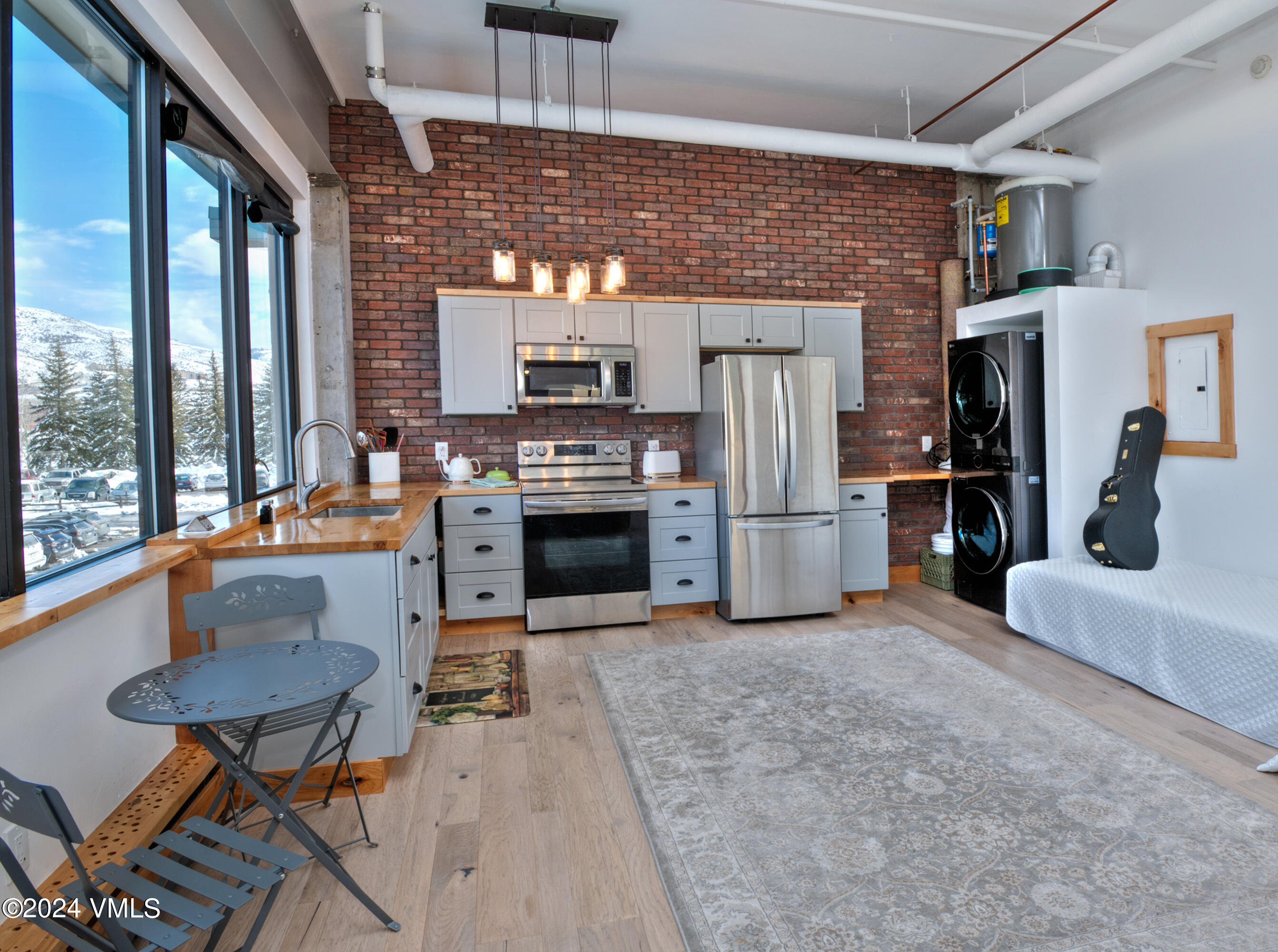 70 Benchmark Road, Unit 201 Avon, CO 81620 - Photo 3 of 32 a open kitchen with stainless steel appliances granite countertop a stove top oven a refrigerator and a fireplace with wooden floor