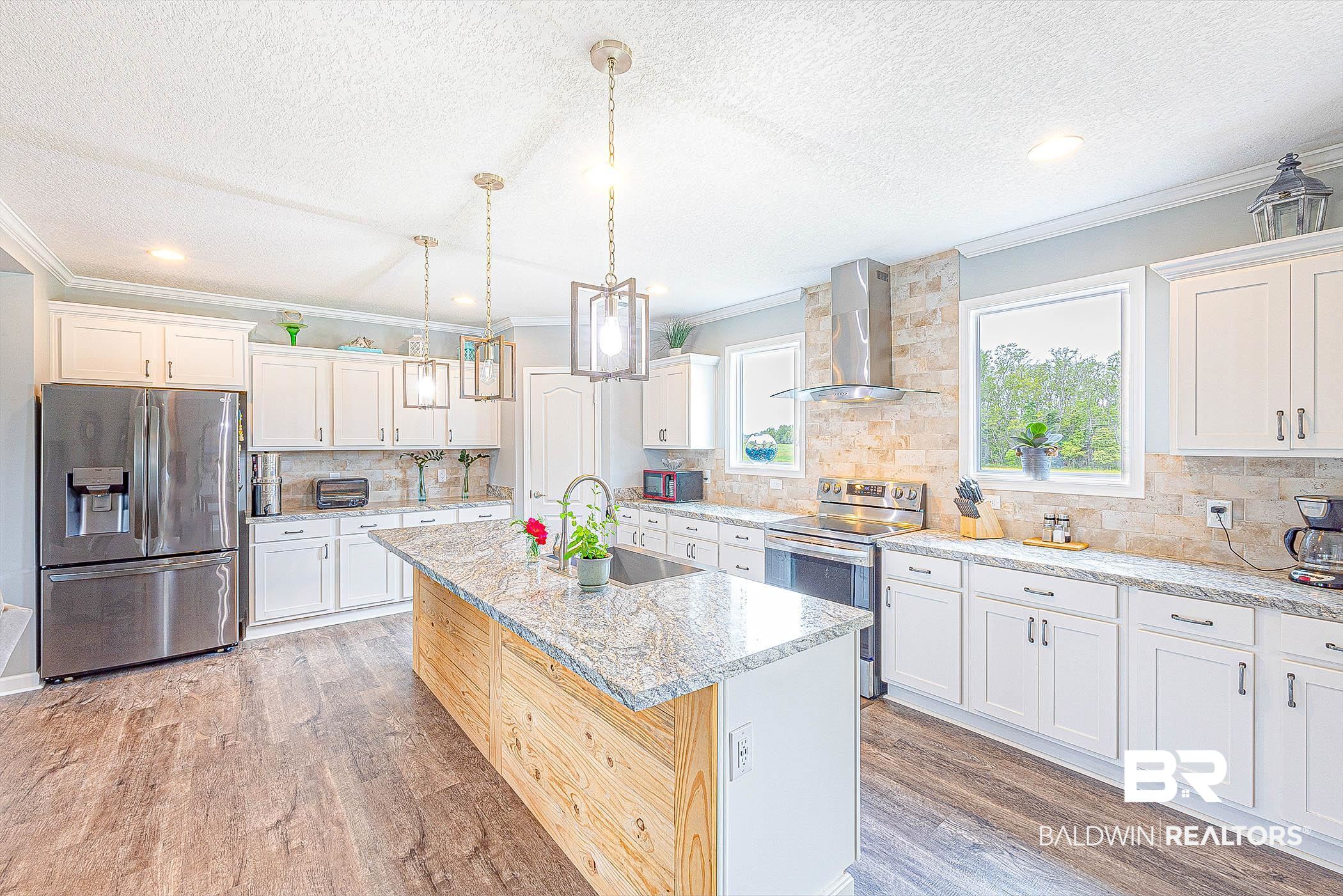 16000 John Bauer Road Summerdale, AL 36580 - Photo 12 of 34 Kitchen featuring white cabinets, wall chimney exhaust hood, a kitchen island with sink, stainless steel appliances, and a sink