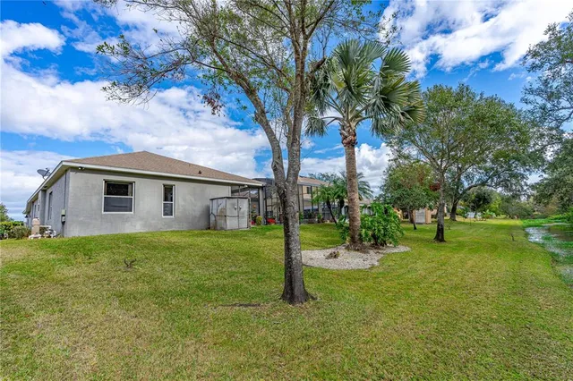 a backyard of a house with plants and large tree