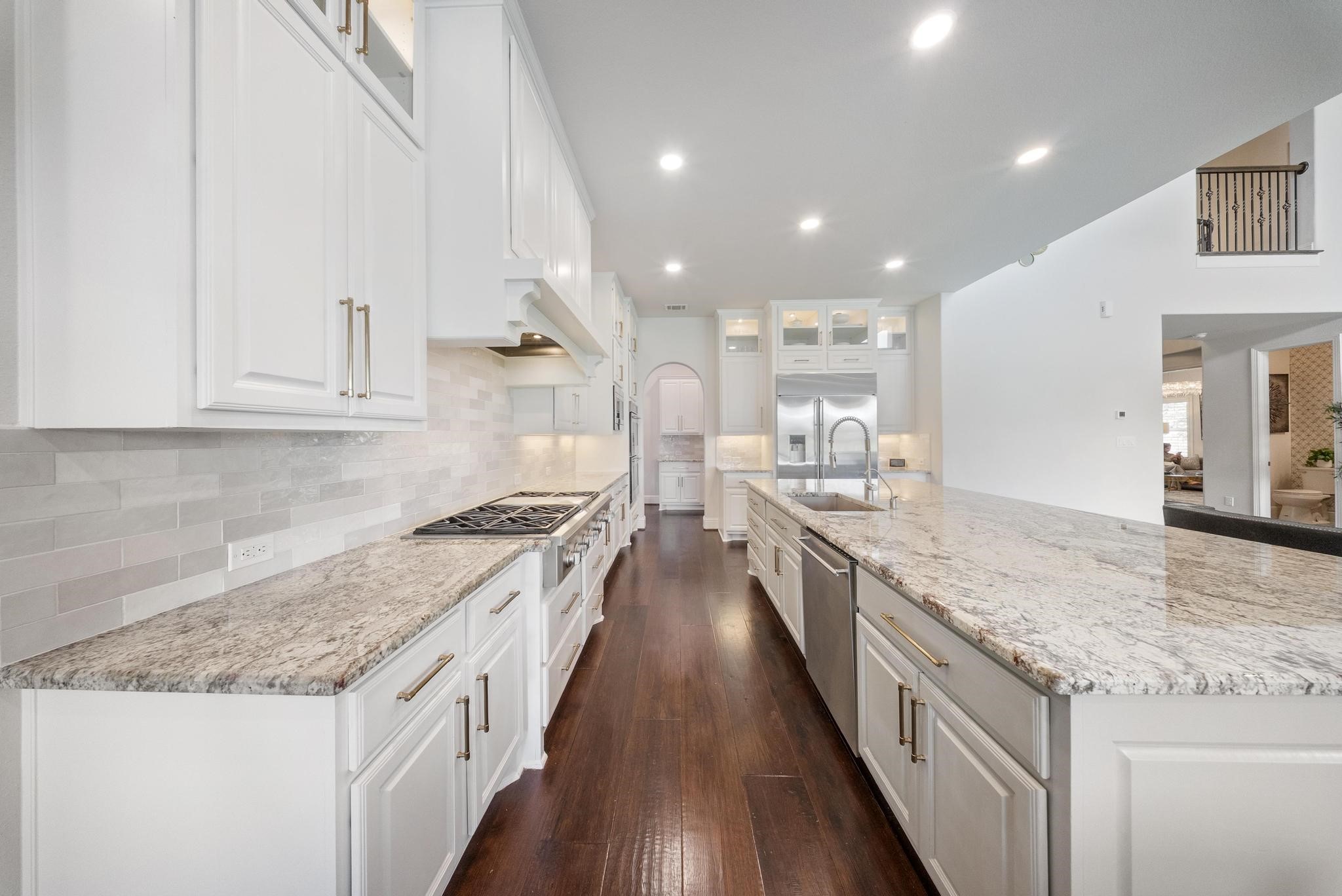 5403 Rouchel Brook Lane Sugar Land, TX 77479 - Photo 11 of 42 Chef-inspired kitchen showcasing custom floor-to-ceiling cabinetry, an oversized island with bar seating, and Monogram stainless steel appliances.