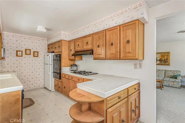 a kitchen with stainless steel appliances granite countertop a stove a refrigerator a sink dishwasher and white cabinets with wooden floor