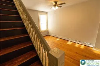 a view of staircase with wooden floor and white walls