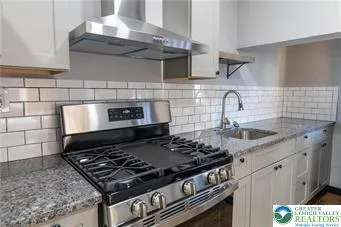 a stove sitting inside of a kitchen with stainless steel appliances granite countertop a stove and a sink