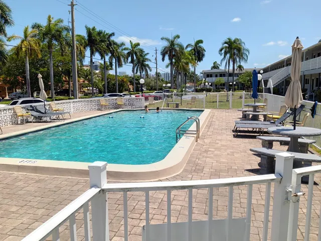 a view of swimming pool with outdoor seating and palm trees