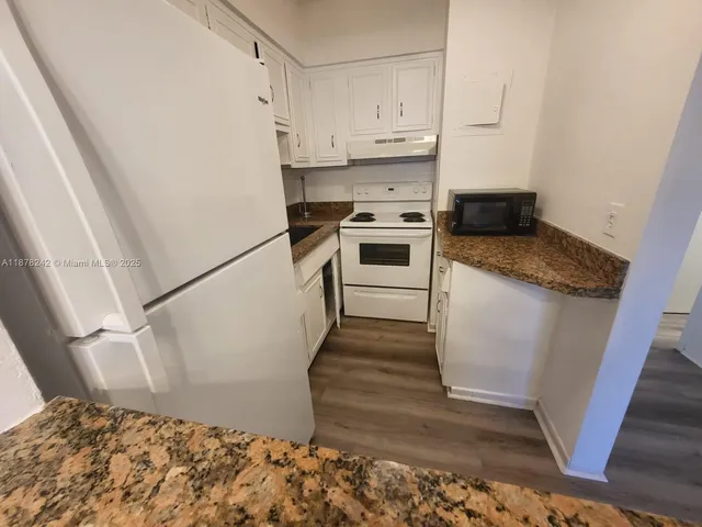 a kitchen with granite countertop white cabinets and white appliances