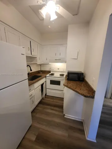 a kitchen with granite countertop white cabinets and white appliances