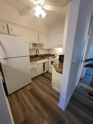 a kitchen with sink a refrigerator and white cabinets