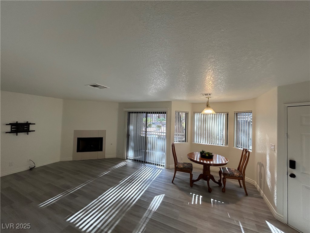 Living area with wood finished floors, a tiled fireplace, and a textured ceiling