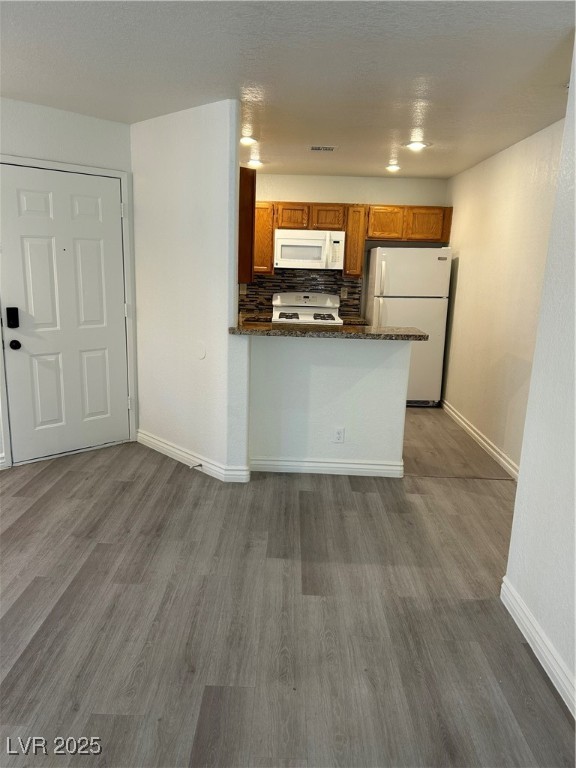 5044 South Rainbow Boulevard, Unit 106 Las Vegas, NV 89118 - Photo 5 of 18 Kitchen with refrigerator, stove, brown cabinetry, and dark wood finished floors