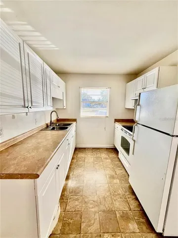 a large white kitchen with a sink and refrigerator