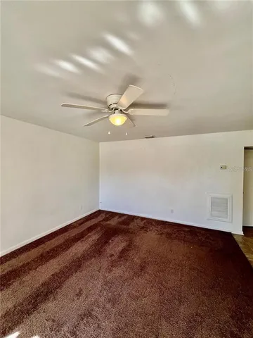 an empty room with a ceiling fan and window