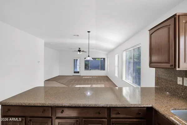 a view of kitchen with granite countertop a sink and a refrigerator