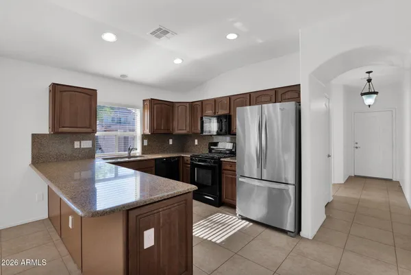 a kitchen with granite countertop a refrigerator and a stove top oven