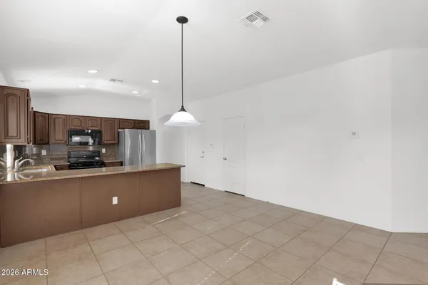 a kitchen with stainless steel appliances a sink a counter top space cabinets and a view of living room