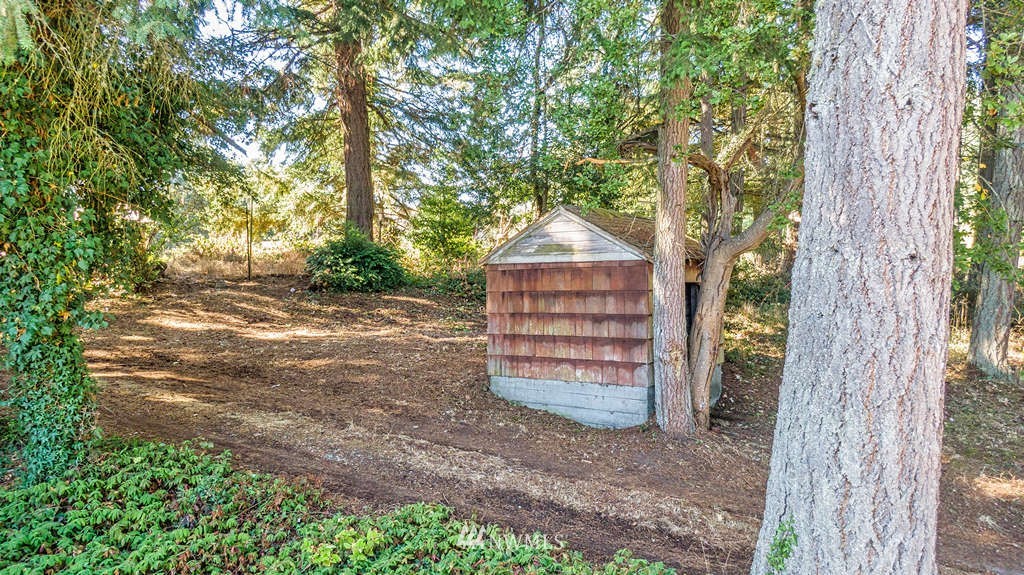 19038 Ridge Road Southwest Vashon, WA 98070 - Photo 35 of 38 a backyard of a house with wooden fence and large trees