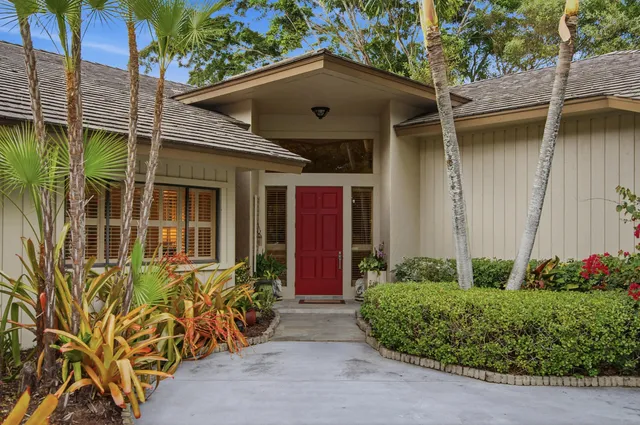 a front view of a house with a garden and trees