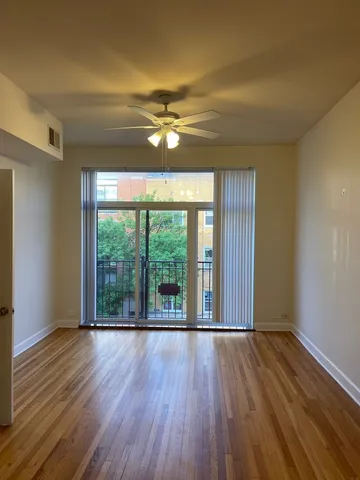 a view of empty room with wooden floor and fan