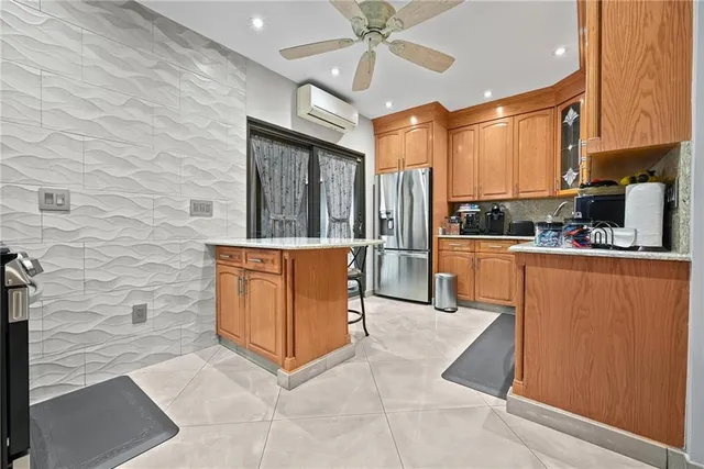 a kitchen with stainless steel appliances kitchen island granite countertop a refrigerator a oven a sink with wooden cabinets and wooden floor