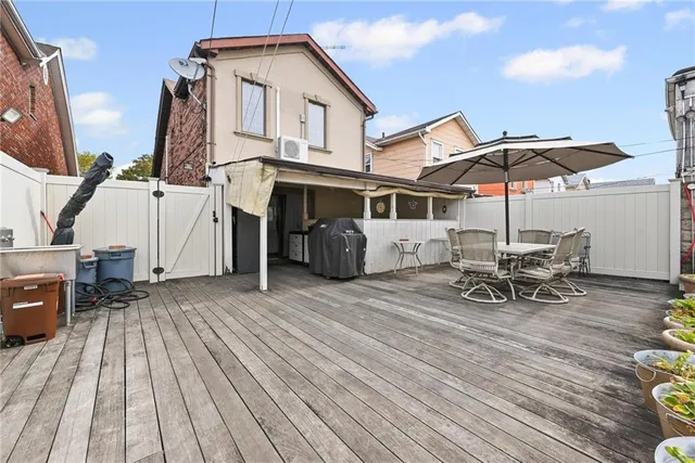 a view of a house with table and chairs under an umbrella with wooden floor