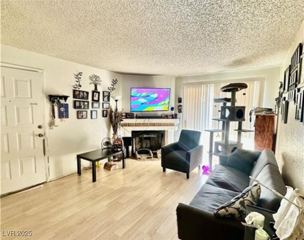 221 Mission Newport Lane, Unit 205 Las Vegas, NV 89107 - Photo 8 of 11 Living area with light wood-style flooring, a textured ceiling, and a fireplace