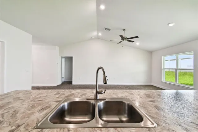 an empty room with windows and ceiling fan