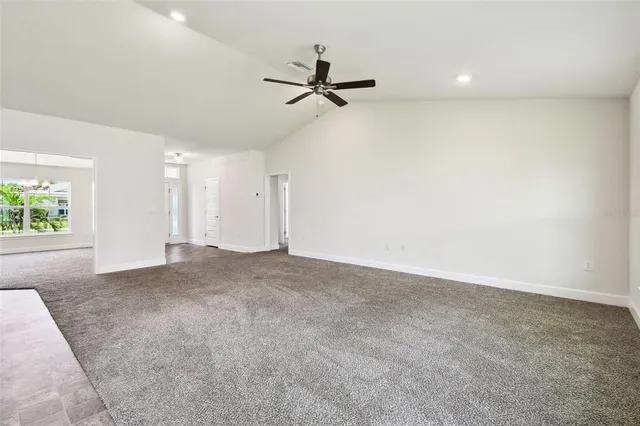 an empty room with windows and chandelier fan